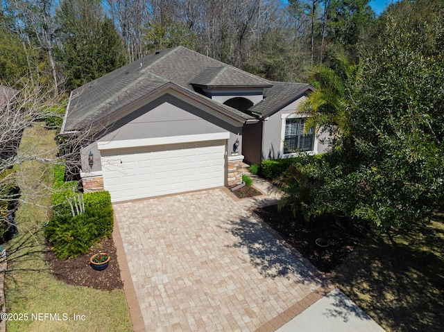 view of front facade with stucco siding, decorative driveway, and a garage