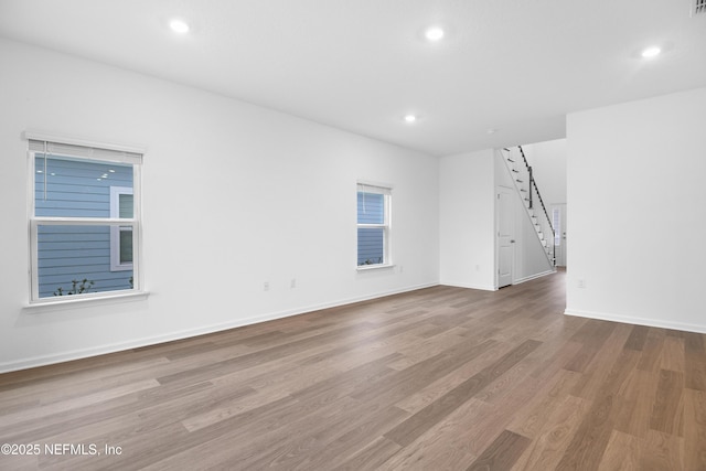 spare room with recessed lighting, a barn door, baseboards, and wood finished floors