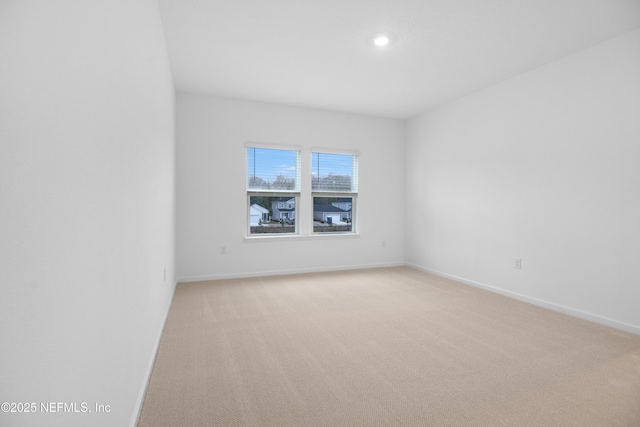 unfurnished room with baseboards and light colored carpet