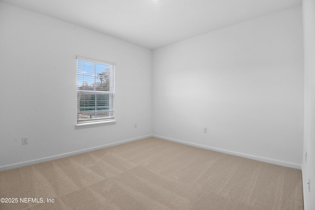 spare room featuring baseboards and light carpet