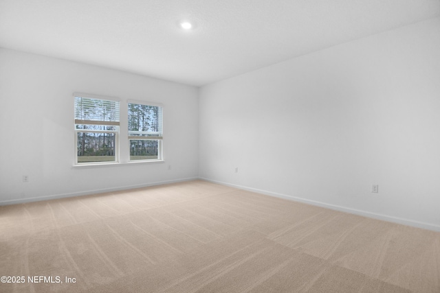 spare room featuring baseboards and light carpet