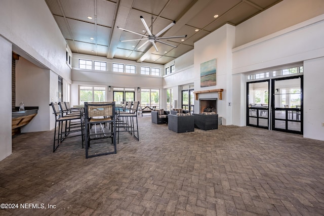 dining area featuring ceiling fan, brick floor, recessed lighting, a high ceiling, and a fireplace