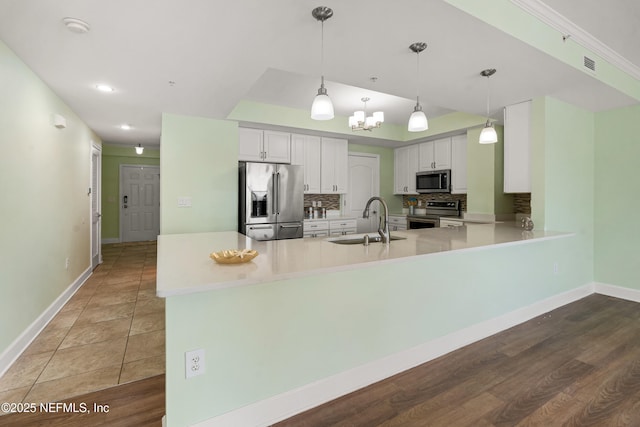 525 3rd St N Unit 303, Jacksonville Beach, FL 32250 - kitchen with tasteful backsplash, appliances with stainless steel finishes, white cabinetry, a sink, and a peninsula