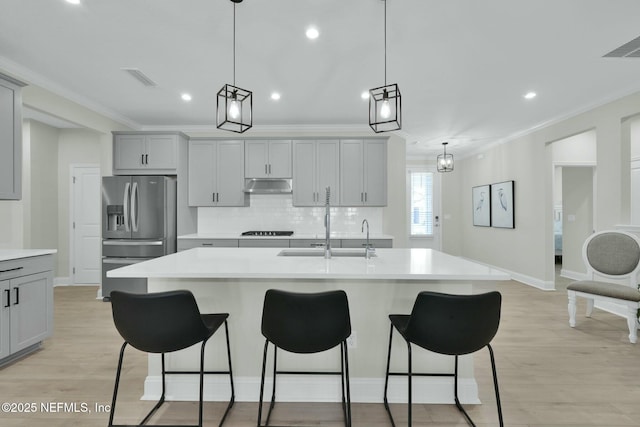 kitchen featuring light countertops, ornamental molding, stainless steel refrigerator with ice dispenser, and under cabinet range hood