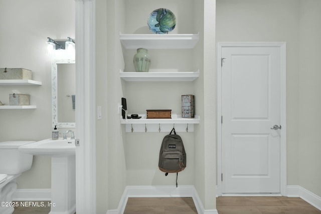 mudroom with a sink, built in shelves, baseboards, and wood finished floors