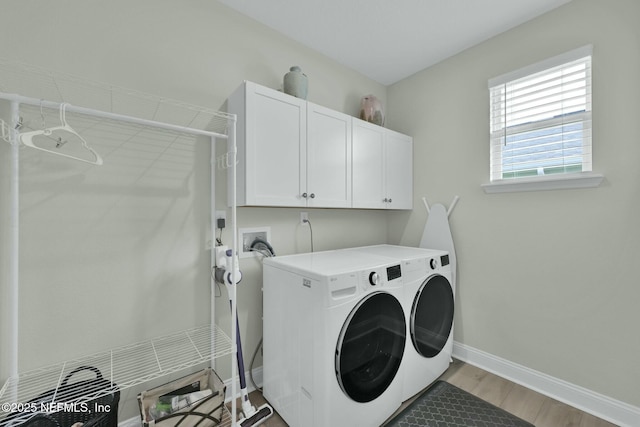 clothes washing area with cabinet space, washing machine and dryer, baseboards, and light wood-style floors