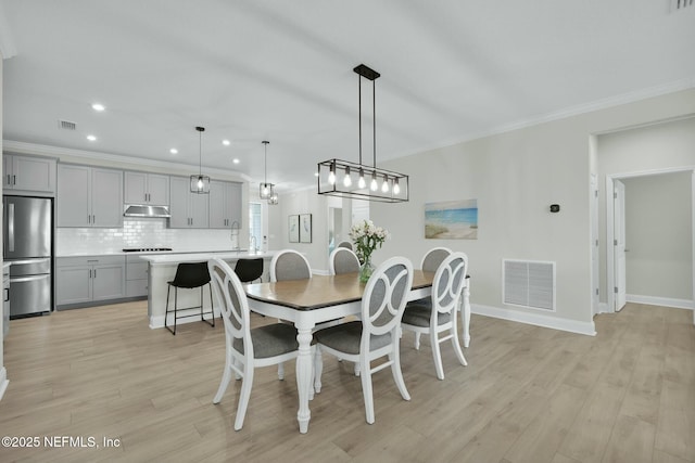 dining room featuring light wood-style floors, visible vents, crown molding, and recessed lighting