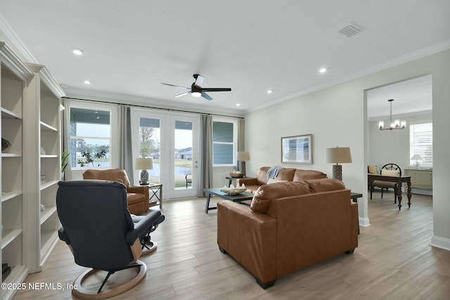 living room featuring light wood finished floors, ornamental molding, ceiling fan with notable chandelier, and visible vents