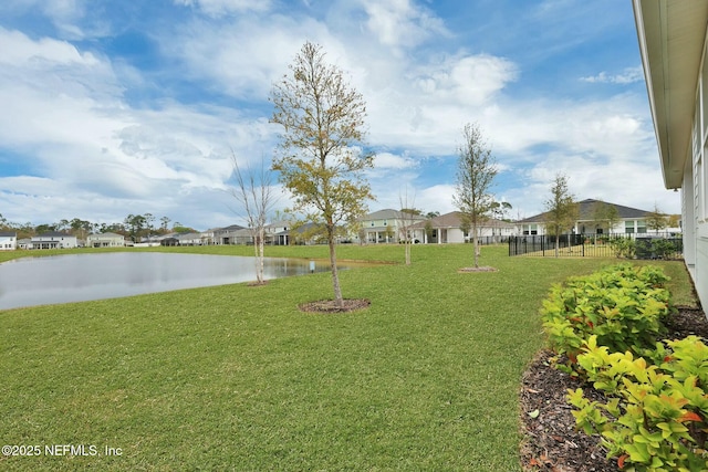 view of yard with a residential view, a water view, and fence