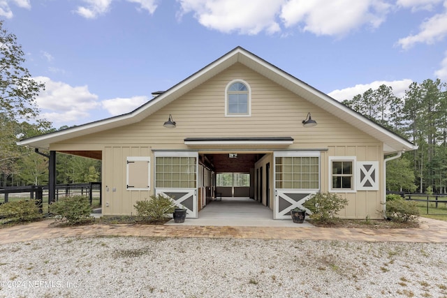 bungalow-style home featuring an outbuilding, an exterior structure, board and batten siding, and gravel driveway