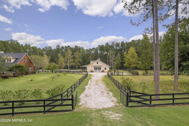 view of gate with an enclosed area, a rural view, fence, and an outdoor structure