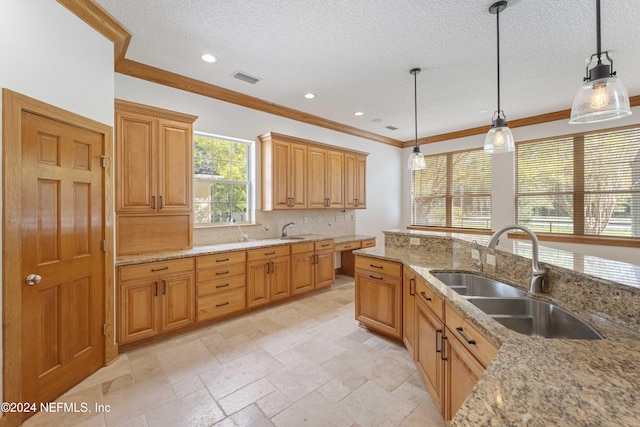 kitchen featuring visible vents, ornamental molding, a sink, decorative light fixtures, and backsplash