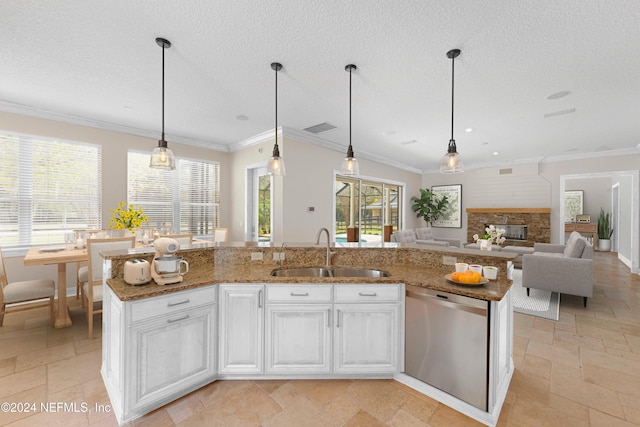 kitchen with light stone countertops, dishwasher, stone tile floors, a fireplace, and a sink