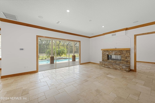 unfurnished living room with visible vents, baseboards, stone tile flooring, a stone fireplace, and a textured ceiling