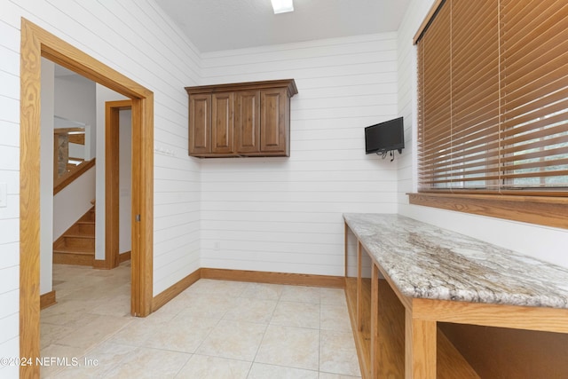 kitchen with light tile patterned floors, baseboards, and light stone countertops