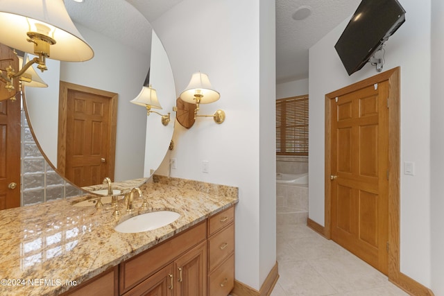 bathroom featuring vanity, baseboards, tile patterned flooring, a textured ceiling, and a bath