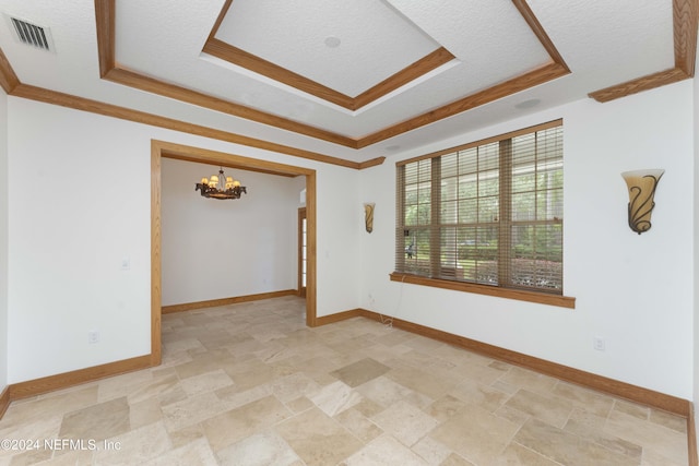 empty room featuring a raised ceiling, a notable chandelier, baseboards, and visible vents