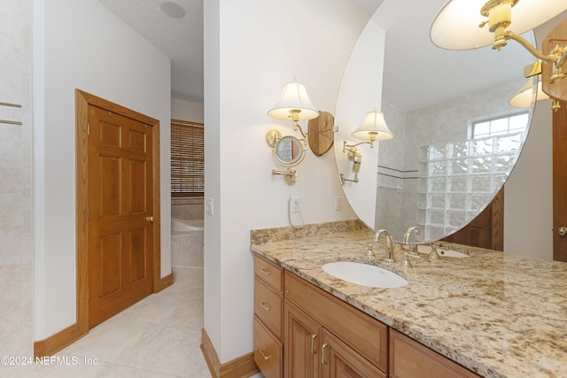 bathroom with vanity, baseboards, a textured ceiling, tile patterned floors, and a bath