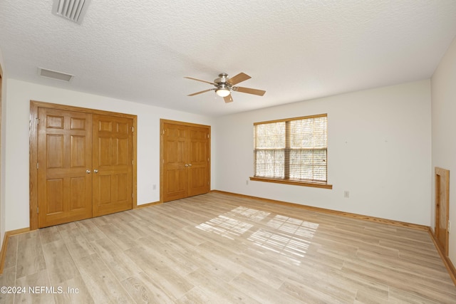 unfurnished bedroom with visible vents, light wood-style floors, and a textured ceiling