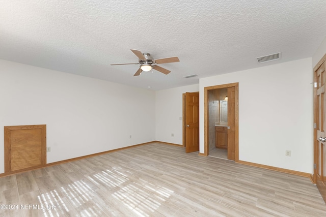 unfurnished bedroom with visible vents, baseboards, light wood-style floors, a textured ceiling, and connected bathroom