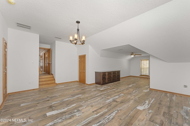 additional living space with visible vents, hardwood / wood-style flooring, a textured ceiling, baseboards, and lofted ceiling