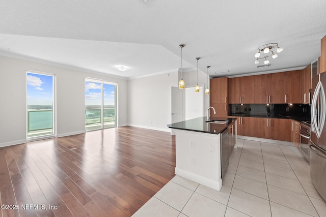 1431 Riverplace Blvd Unit 2606, Jacksonville, FL 32207 - kitchen with open floor plan, a sink, dark countertops, a kitchen island with sink, and brown cabinetry