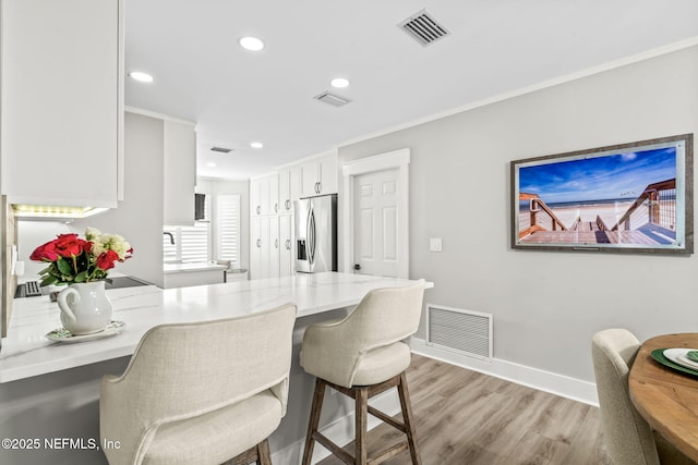 dining room featuring light wood-type flooring, visible vents, baseboards, and crown molding