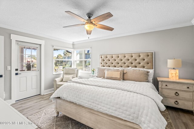 bedroom with ornamental molding, a textured ceiling, wood finished floors, baseboards, and ceiling fan