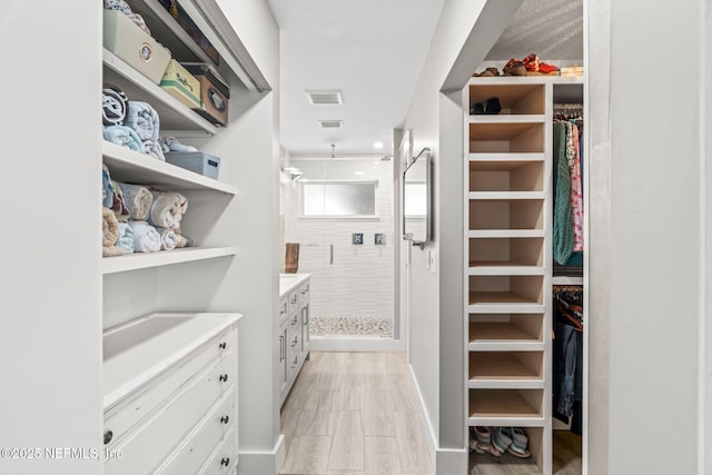 spacious closet with light wood-style flooring and visible vents