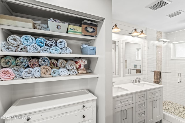 bathroom featuring a sink, visible vents, and a shower stall