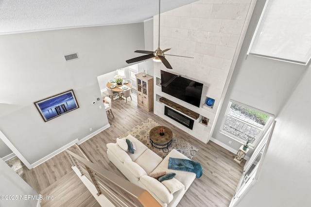 living area featuring visible vents, high vaulted ceiling, baseboards, and wood finished floors