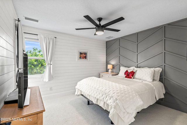 carpeted bedroom featuring visible vents, a textured ceiling, and a ceiling fan