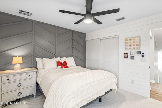 bedroom with a decorative wall, light colored carpet, and visible vents