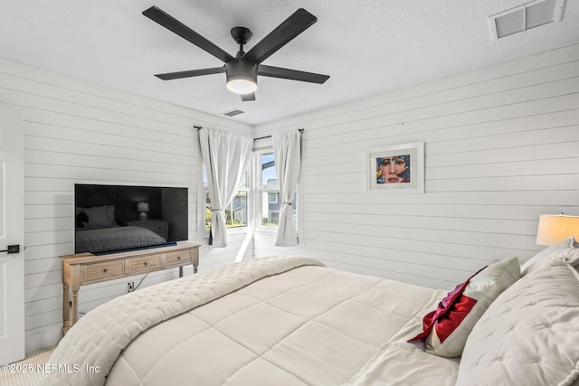 bedroom with a ceiling fan, visible vents, and a textured ceiling