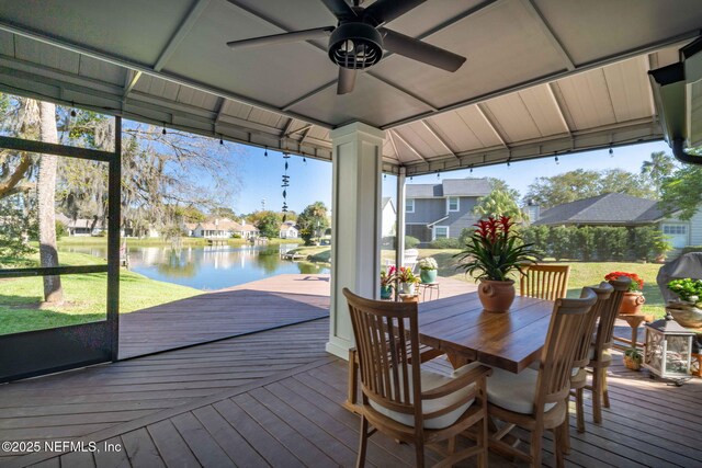 sunroom / solarium featuring a ceiling fan and a water view