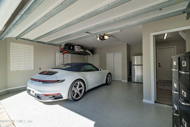 garage featuring baseboards, a garage door opener, and freestanding refrigerator