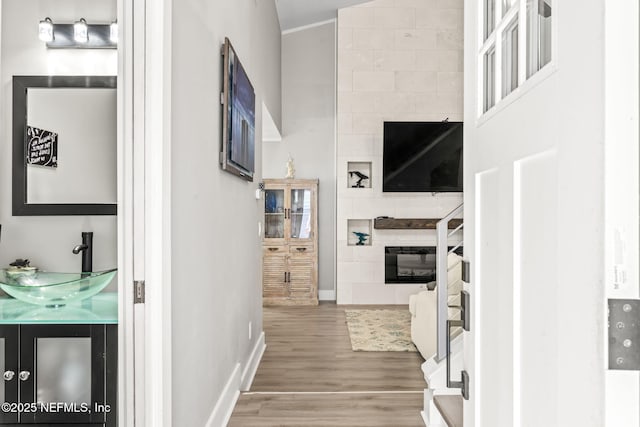 corridor with wood finished floors, baseboards, and a sink