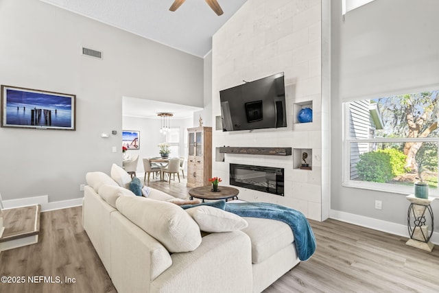 living room featuring visible vents, baseboards, high vaulted ceiling, and wood finished floors