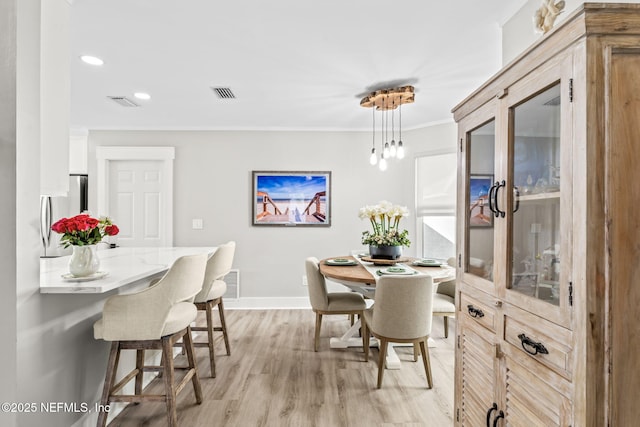 dining room featuring visible vents, ornamental molding, recessed lighting, light wood finished floors, and baseboards