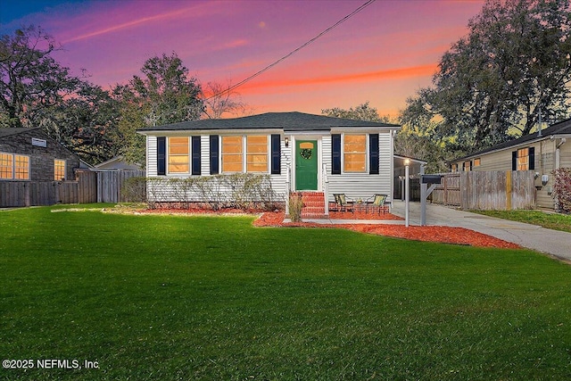 view of front of home featuring entry steps, concrete driveway, a front yard, and fence