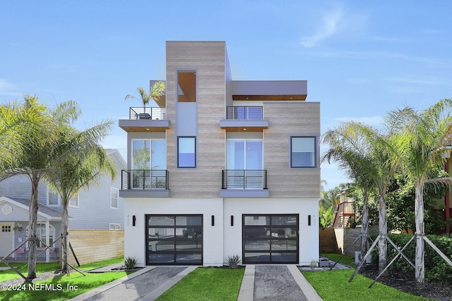 contemporary house featuring an attached garage, driveway, and a front lawn