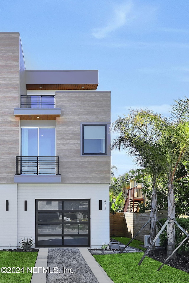 contemporary home featuring an attached garage, fence, and a balcony