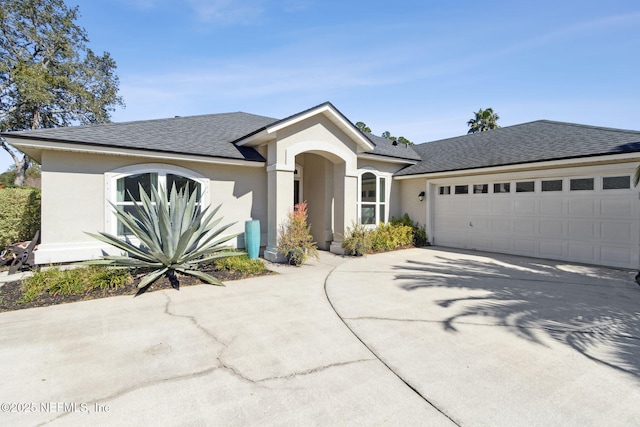 ranch-style home with an attached garage, roof with shingles, concrete driveway, and stucco siding