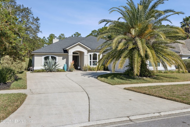 view of front of house with roof with shingles, a chimney, stucco siding, a front yard, and driveway