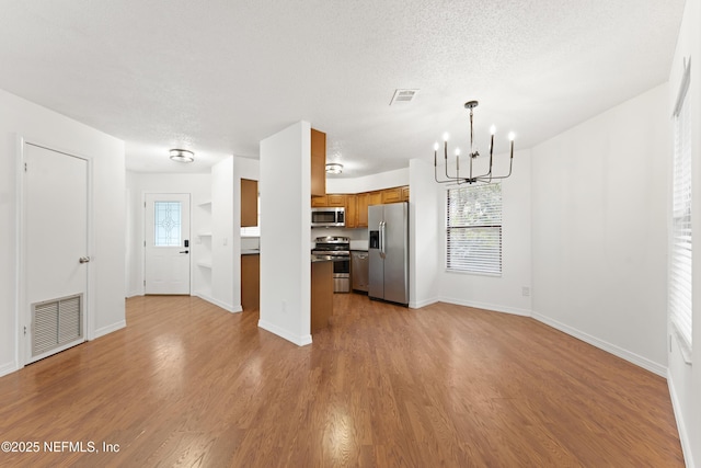 kitchen with brown cabinetry, visible vents, appliances with stainless steel finishes, and open floor plan