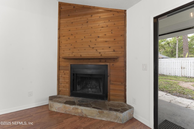 details featuring a stone fireplace, baseboards, and wood finished floors