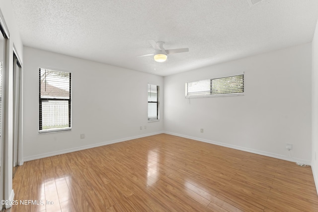 unfurnished room featuring light wood-style flooring, a ceiling fan, and a wealth of natural light