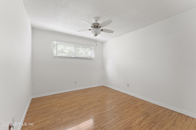 spare room featuring light wood finished floors, a textured ceiling, baseboards, and a ceiling fan