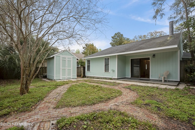 back of property with a patio, an outbuilding, fence, a yard, and a shed