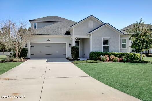 view of front of home with a front yard, an attached garage, and driveway